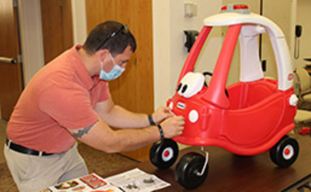 Chad Vorderbrueggen applies stickers to a riding vehicle